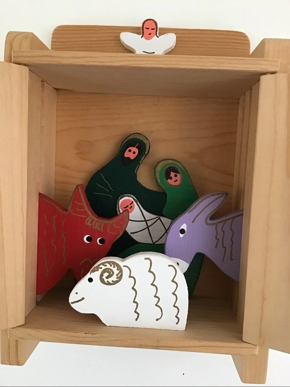 Handmade wooden cabinet holding a small wooden Nativity set